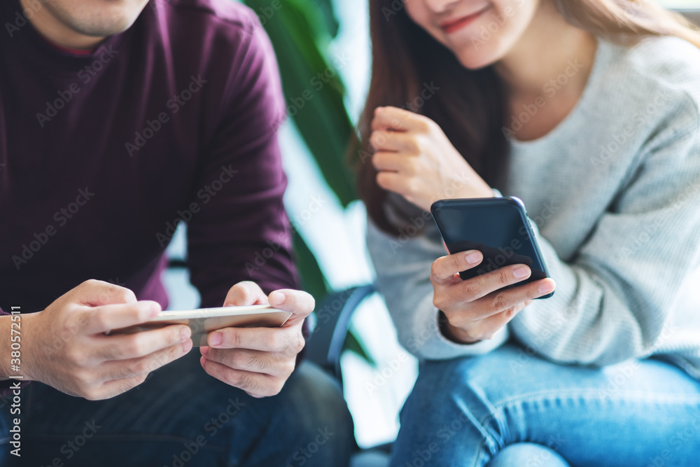 Young people using and playing games on mobile phone while sitting together Young people using and playing games on mobile phone while sitting together