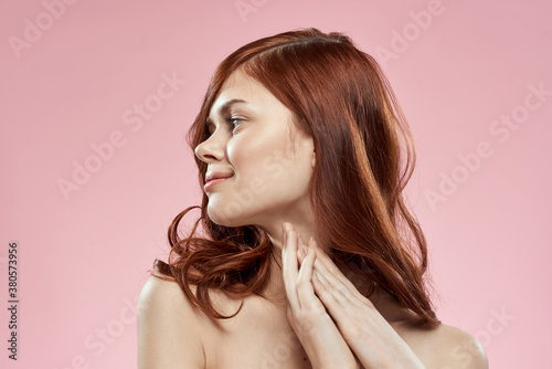 Pretty woman with long beautiful hair grooming hairstyle glamor naked shoulders pink background