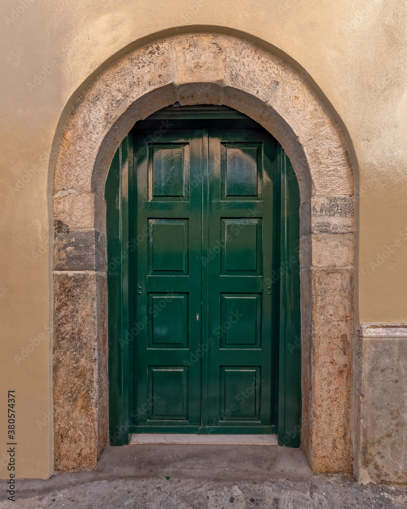 dark green painted door with arched stone frame