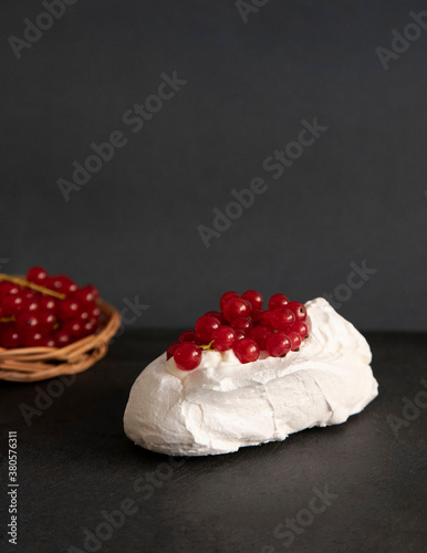 Mini Pavlova with whipped cream and redcurrant. Meringue dessert. dark background, front view