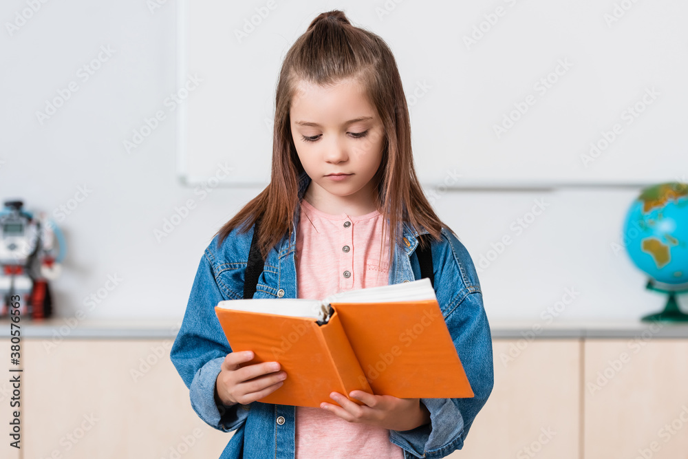 Schoolgirl with backpack reading book in stem school Schoolgirl with backpack reading book in stem school