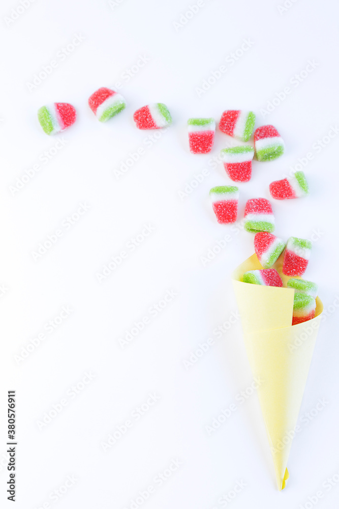 Watermelon jelly beans spilling from a paper cone with copy space.