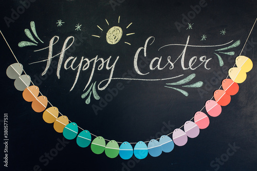 Happy Easter message on a blackboard with paper egg banner