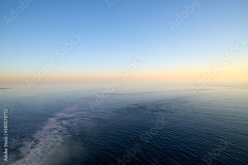 View on water of sea and pink and yellow sunset on horizon in background