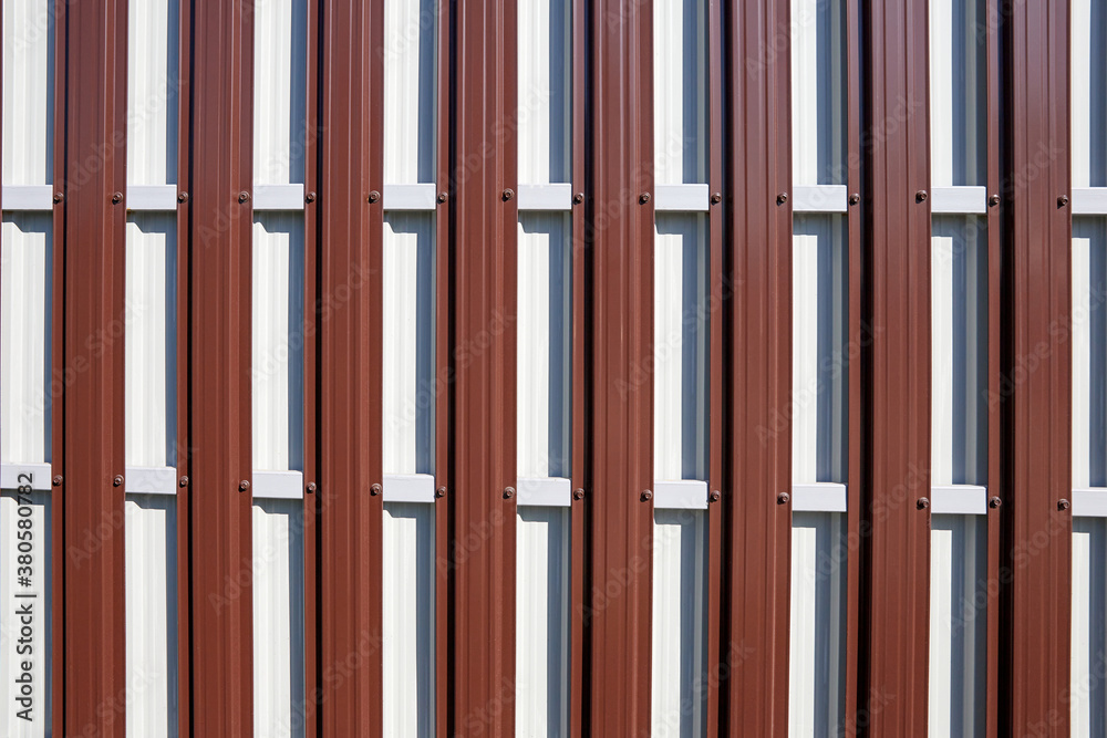 The reverse side of the fence made of corrugated board as a red-white background