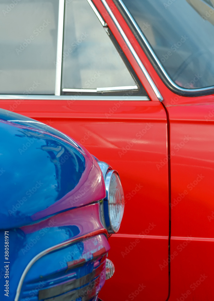 Fototapeta premium Headlight of a blue vintage car on the background of a red car close-up