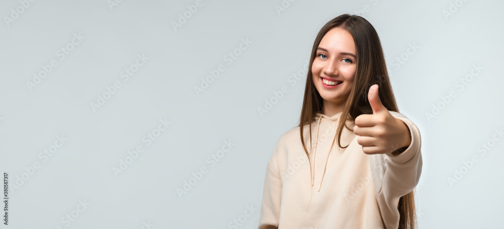 Happy Pretty young woman with long chestnut hair, Smiling and showing thumb up. Human emotions concept. Copy space Happy Pretty young woman with long chestnut hair, Smiling and showing thumb up. Human emotions concept. Copy space