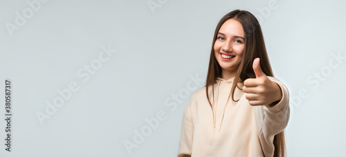 Happy Pretty young woman with long chestnut hair, Smiling and showing thumb up. Human emotions concept. Copy space