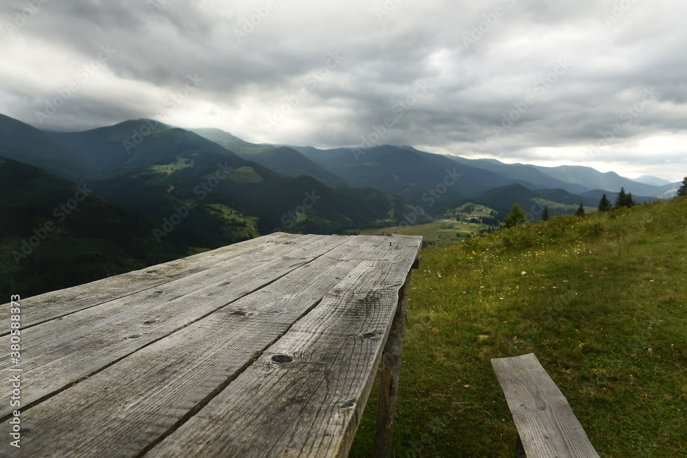 A rough wooden table and bench overlooking a dramatic mountain landscape. A rough wooden table and bench overlooking a dramatic mountain landscape.