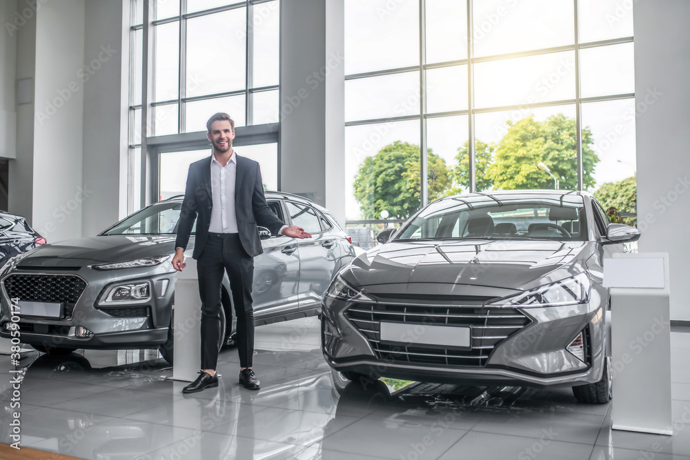 Stylish man in black suit standing near new car Stylish man in black suit standing near new car