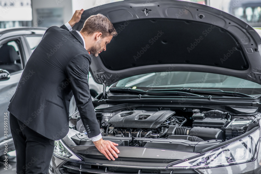 Man in a black suit looking at the car engine Man in a black suit looking at the car engine