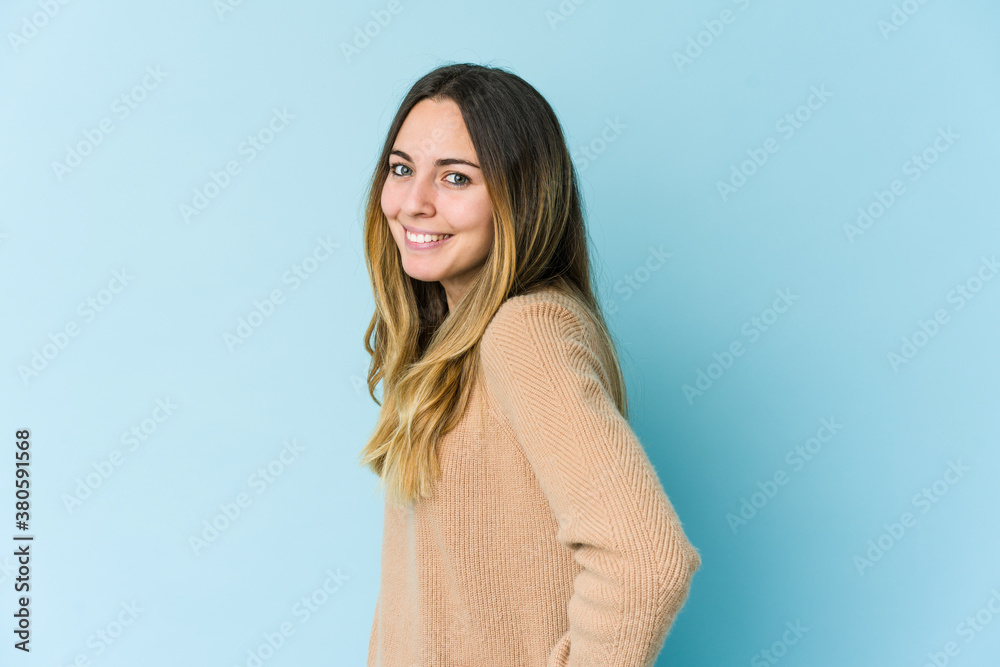 Fototapeta premium Young caucasian woman isolated on blue background confident keeping hands on hips.