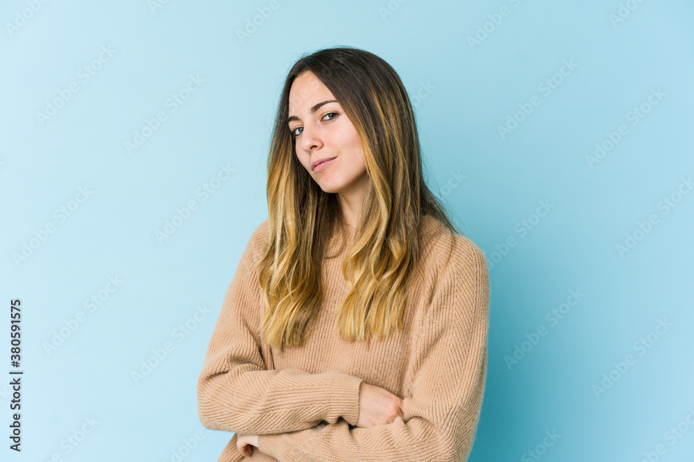 Young caucasian woman isolated on blue background suspicious, uncertain, examining you. Young caucasian woman isolated on blue background suspicious, uncertain, examining you.