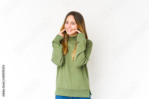 Young caucasian woman isolated on white background smiles, pointing fingers at mouth. © Asier