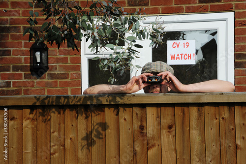 Fotografie Nosy neighbor peeking over the fence, spying on his neighbours during the covid-
