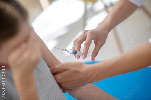 Girl sitting on a couch and looking afraid of vaccination