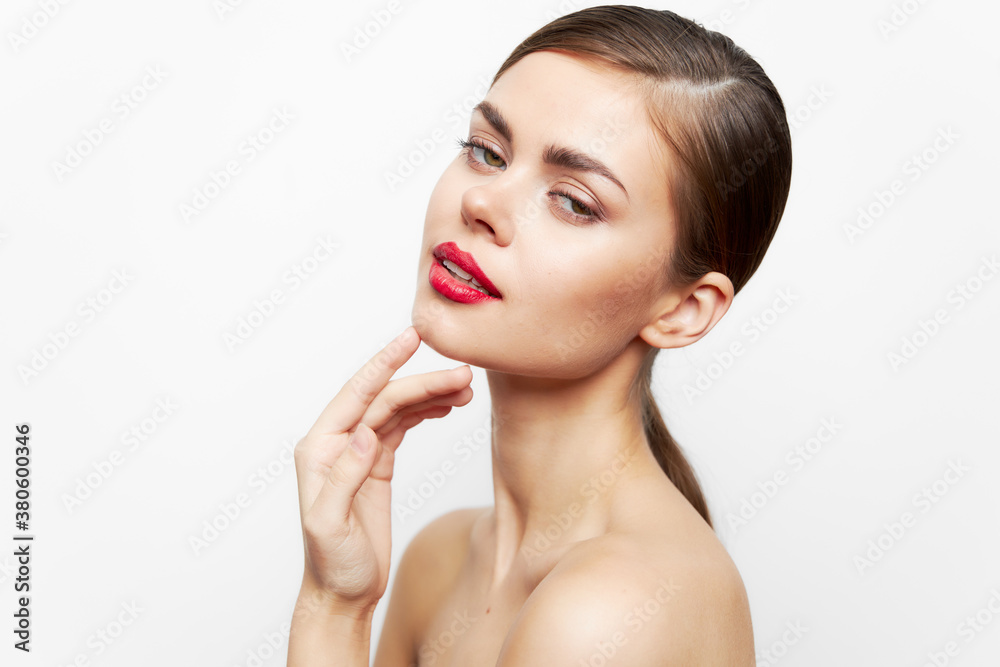 Woman with bare shoulders Holds his hand near the face for an attractive look red lips light 