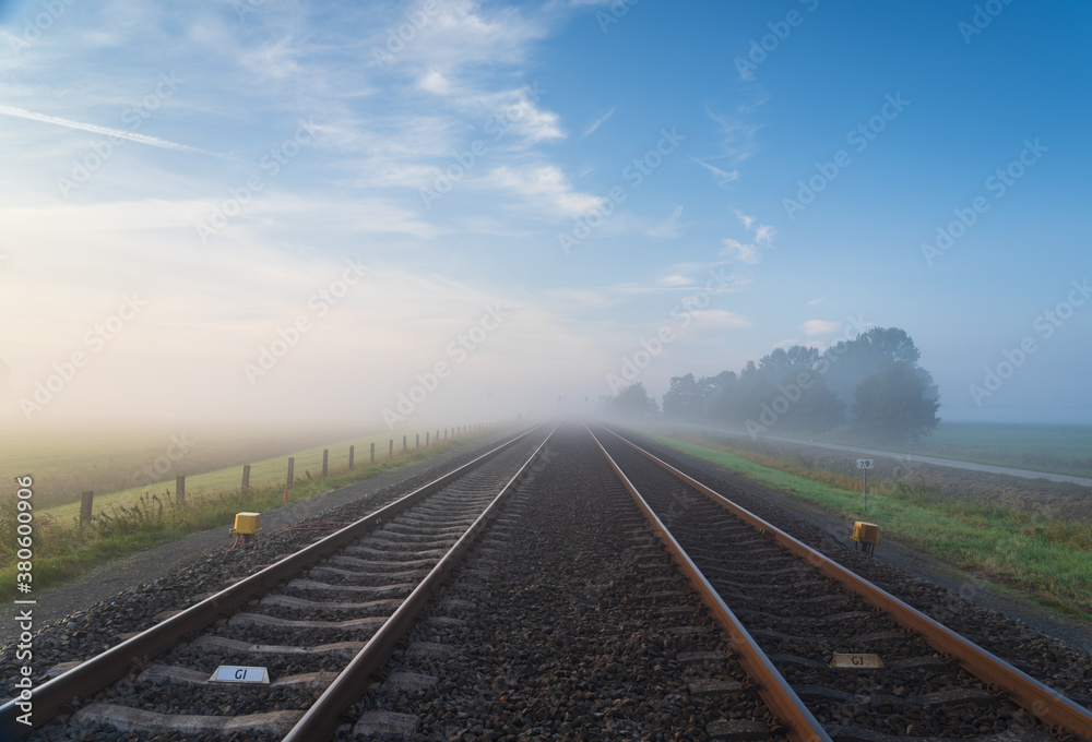 Fototapeta premium Empty railroad tracks disappearing into the spring fog.