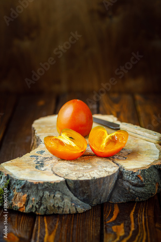 still life with persimmons on wooden background. vertical image. selective focus