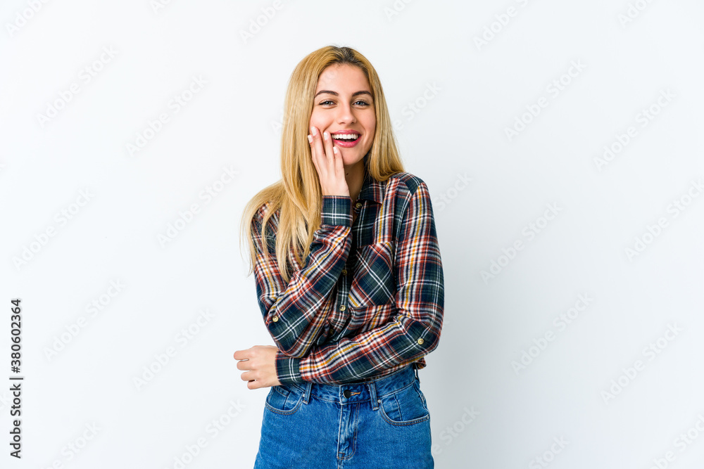 Young blonde woman isolated on white background laughs happily and has fun keeping hands on stomach. Young blonde woman isolated on white background laughs happily and has fun keeping hands on stomach.
