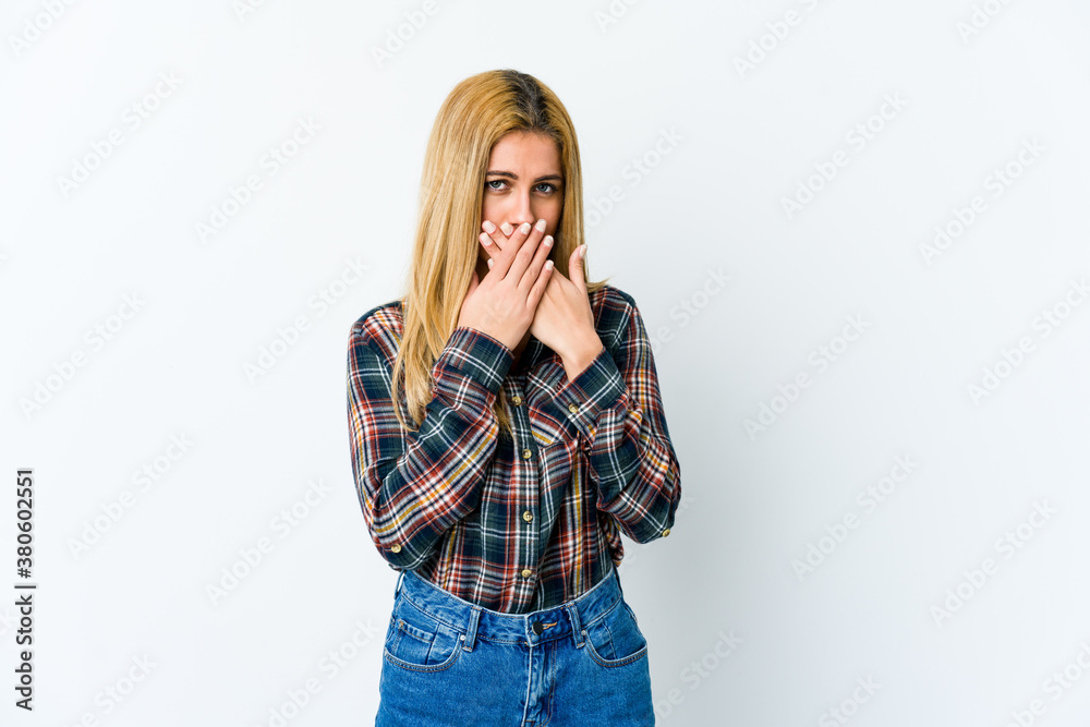 Young blonde woman isolated on white background covering mouth with hands looking worried. Young blonde woman isolated on white background covering mouth with hands looking worried.