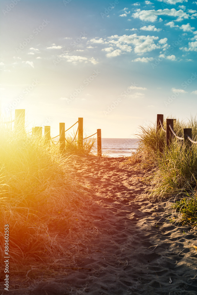Retro style photo of a r sandy pathway with grass reeds and wooden posts on each side leading to a beautiful sea bay Retro style photo of a r sandy pathway with grass reeds and wooden posts on each side leading to a beautiful sea bay