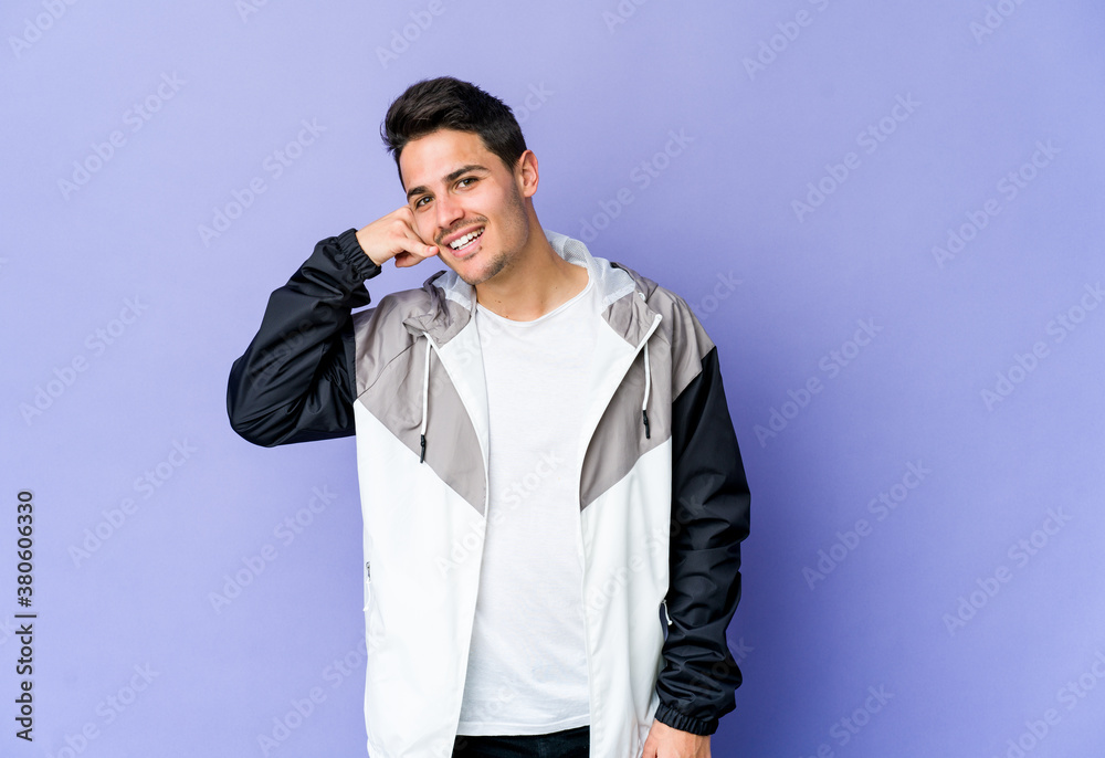 Young caucasian man isolated on purple background showing a mobile phone call gesture with fingers. Young caucasian man isolated on purple background showing a mobile phone call gesture with fingers.