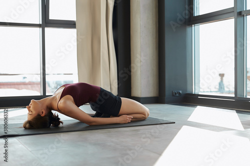 Strong woman bodybuilder stretching upside down in urban interior.