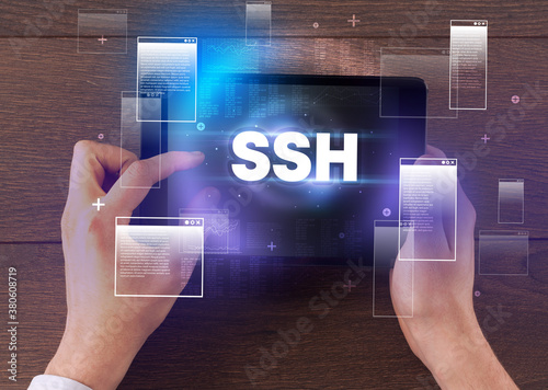 Close-up of a hand holding tablet with SSH abbreviation, modern technology concept
