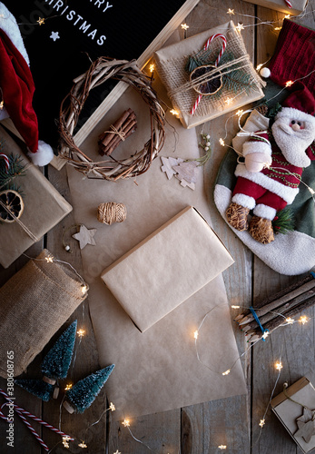 Christmas holiday gift wrapped in craft paper on wooden background.