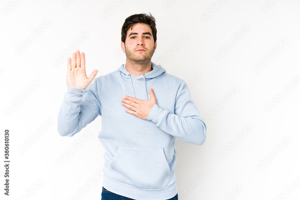 Young man isolated on white background taking an oath, putting hand on chest. Young man isolated on white background taking an oath, putting hand on chest.
