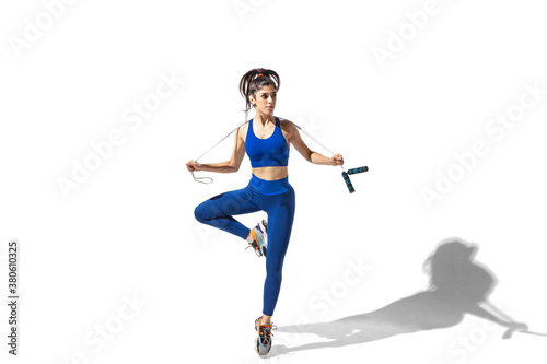 Movement. Beautiful young female athlete practicing on white studio background, portrait with shadows. Sportive fit model in motion and action. Body building, healthy lifestyle, style concept.