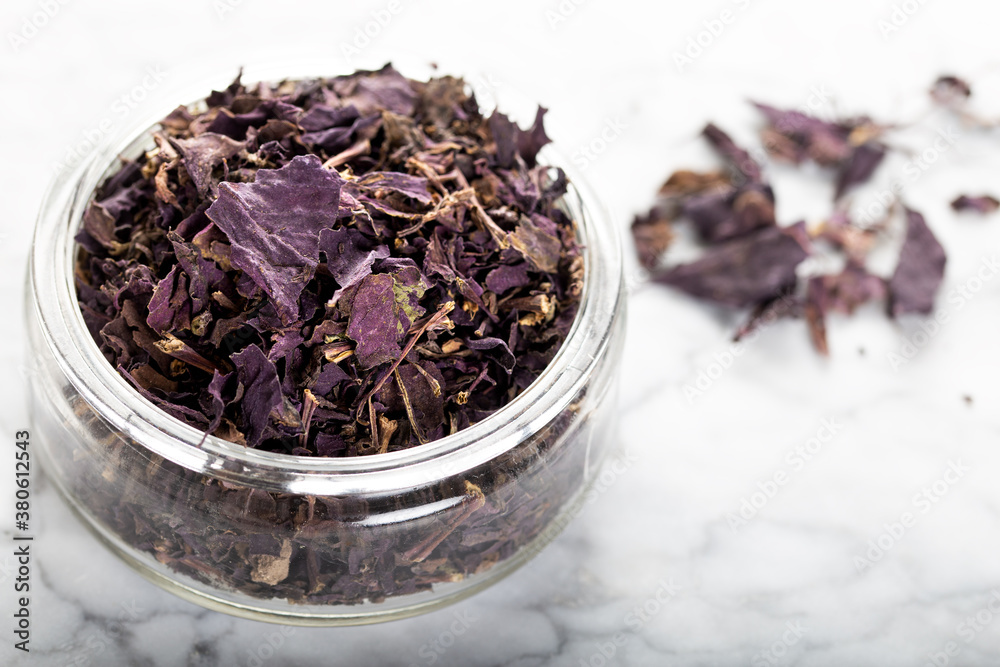 Fototapeta premium Dried Basil Leaves in glass jar on stone board.