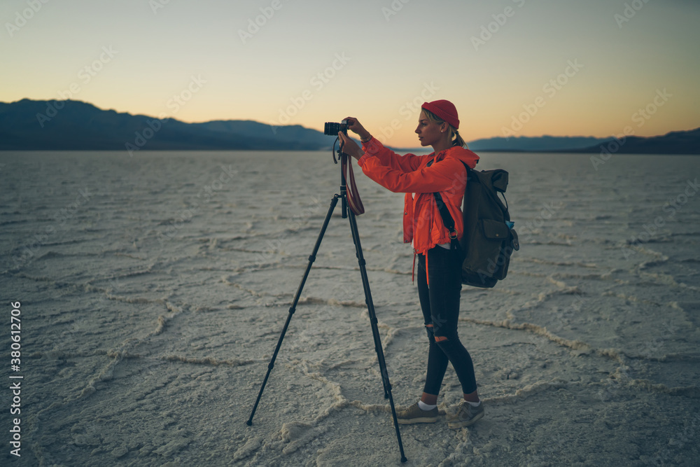 Focused woman adjusting photo camera on tripod