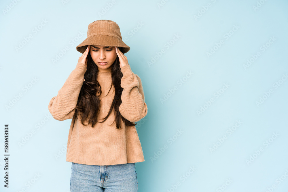 Young indian woman wearing a hat isolated on blue background touching temples and having headache. Young indian woman wearing a hat isolated on blue background touching temples and having headache.