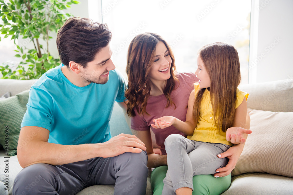 Photo of idyllic family portrait father mother little child girl have communication say tell news sit couch in house indoors Photo of idyllic family portrait father mother little child girl have communication say tell news sit couch in house indoors