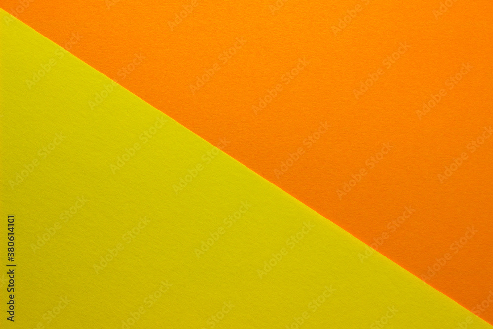Background of yellow and orange paper divided diagonally. Sheets of blank orange and yellow paper with fine texture, close up.