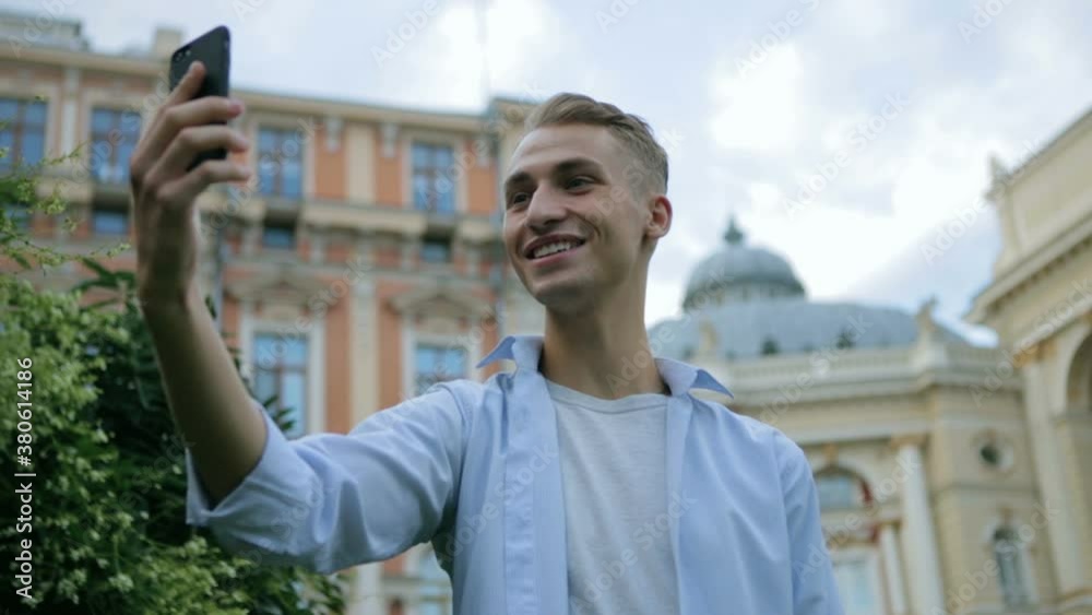 handsome guy talks on video call holding modern smartphone in hand against ancient building slow motion closeup handsome guy talks on video call holding modern smartphone in hand against ancient building slow motion closeup