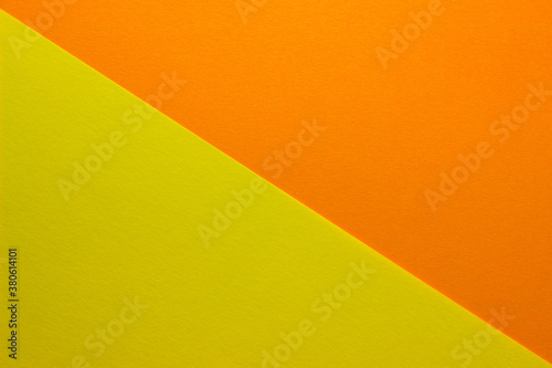 Background of yellow and orange paper divided diagonally. Sheets of blank orange and yellow paper with fine texture, close up.