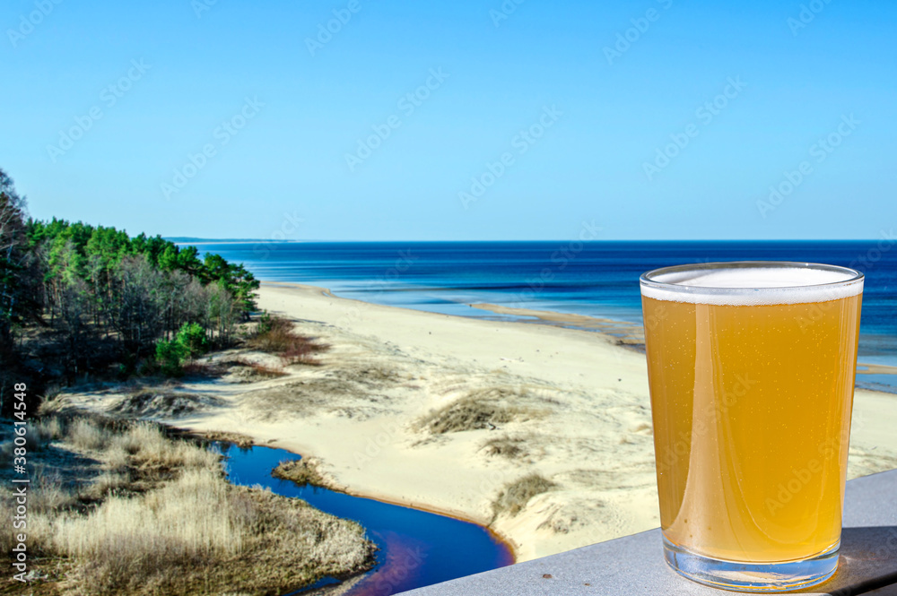 Glass of light beer with view of the white sand beach and Baltic see in spring, Latvia. Glass of light beer with view of the white sand beach and Baltic see in spring, Latvia.