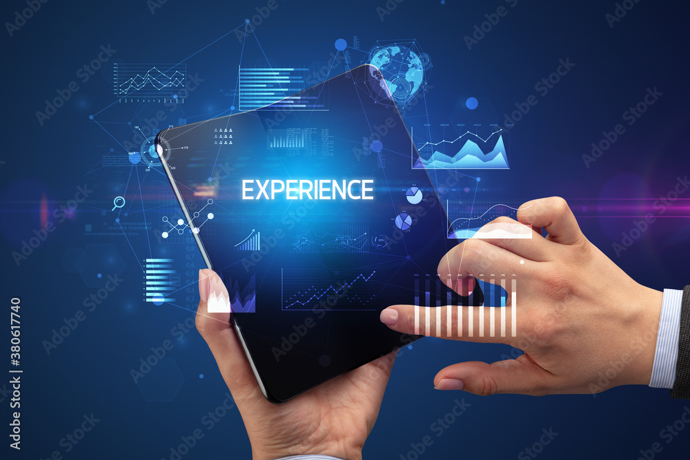 Businessman holding a foldable smartphone with EXPERIENCE inscription, successful business concept Businessman holding a foldable smartphone with EXPERIENCE inscription, successful business concept