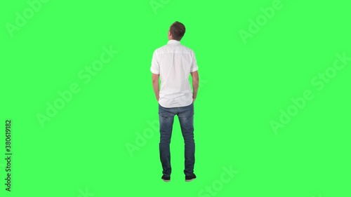 Back view of amazed interested young man watching shop window or gallery copy space. Full body on green screen chroma key background.