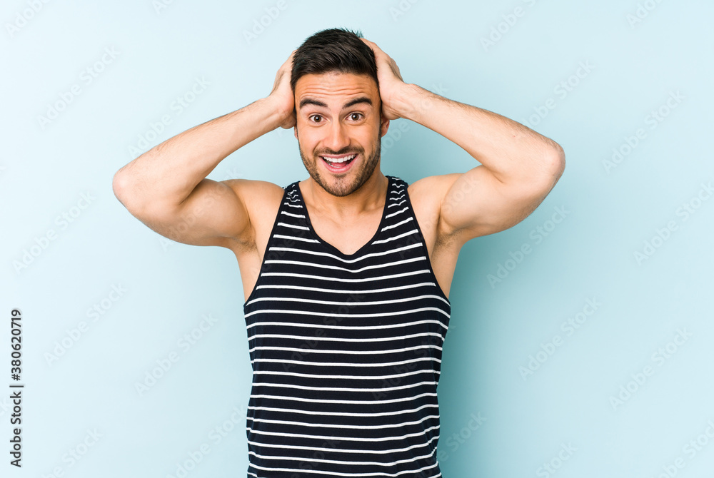 Young caucasian man isolated on blue background screaming, very excited, passionate, satisfied with something. Young caucasian man isolated on blue background screaming, very excited, passionate, satisfied with something.