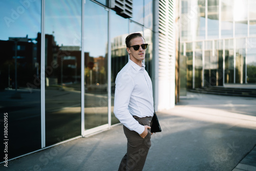 Successful man with hand in pocket near modern glass building