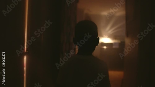 A boy walks down a dimly lit hallway photo