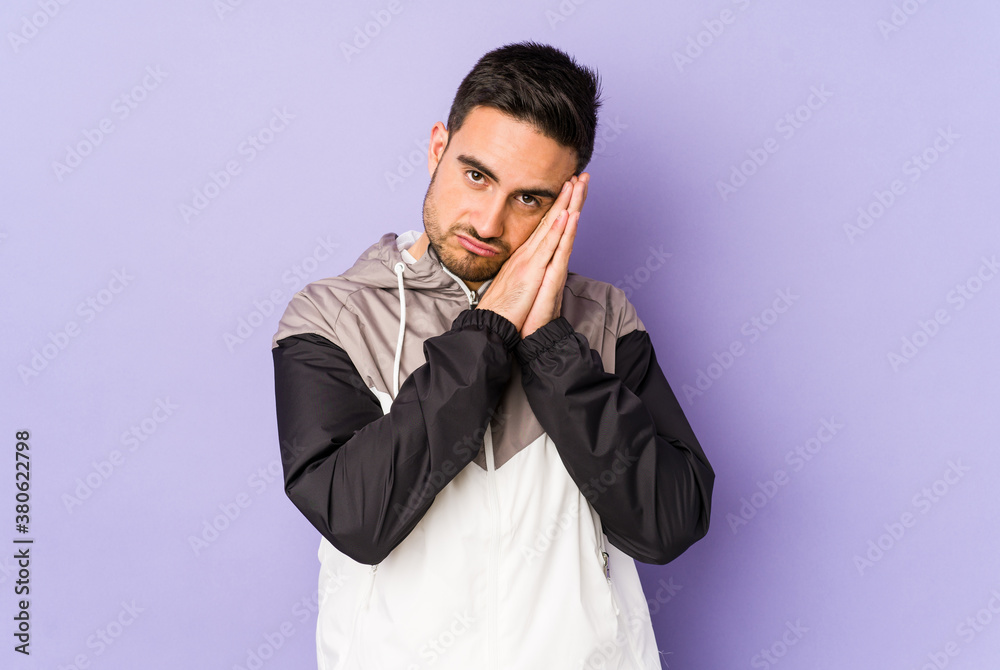 Fototapeta premium Young caucasian man isolated on purple background yawning showing a tired gesture covering mouth with hand.
