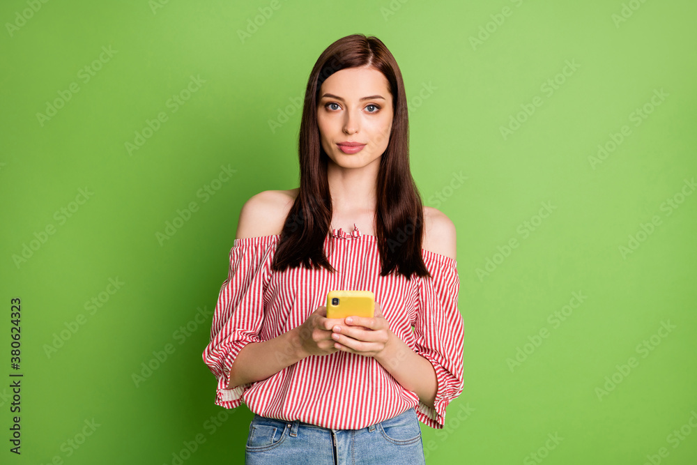 Photo of cute lovely student lady smile hold telephone chatting boyfriend appoint evening date wear denim striped white red shirt uncovered shoulders bright green color background