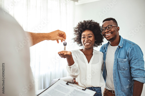 Couple Getting Keys From Realtor Of Their New Home. Portrait of financial adviser congratulating to a young couple for buying a new house. African-American  family buy new house