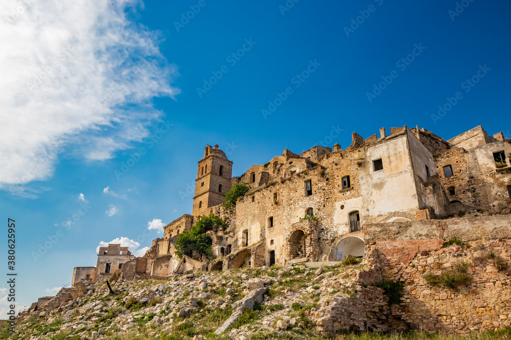 Craco, Basilicata, Italy. Ghost town destroyed and abandoned following a landslide. Collapsed houses and the remains invaded by vegetation. Broken walls, windows and doors. Bell tower of the church