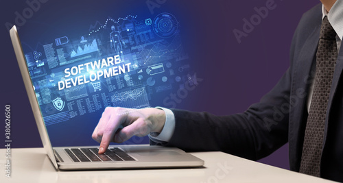 Businessman working on laptop with SOFTWARE DEVELOPMENT inscription, cyber technology concept